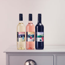 Load image into Gallery viewer, Three wine bottles with colorful labels on a white surface.