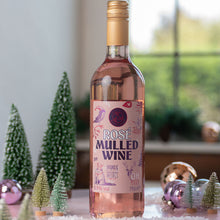 Load image into Gallery viewer, A bottle of Rose Mulled Wine by Celtic Marches stands on a tabletop decorated with miniature Christmas trees, ornaments, and white faux snow, with a softly blurred indoor window background.

