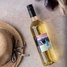 Load image into Gallery viewer, Wine bottle with a smartphone displaying a video call on a textured surface with a straw hat.
