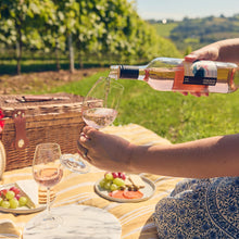 Load image into Gallery viewer, Person pouring wine into a glass at a picnic in a vineyard
